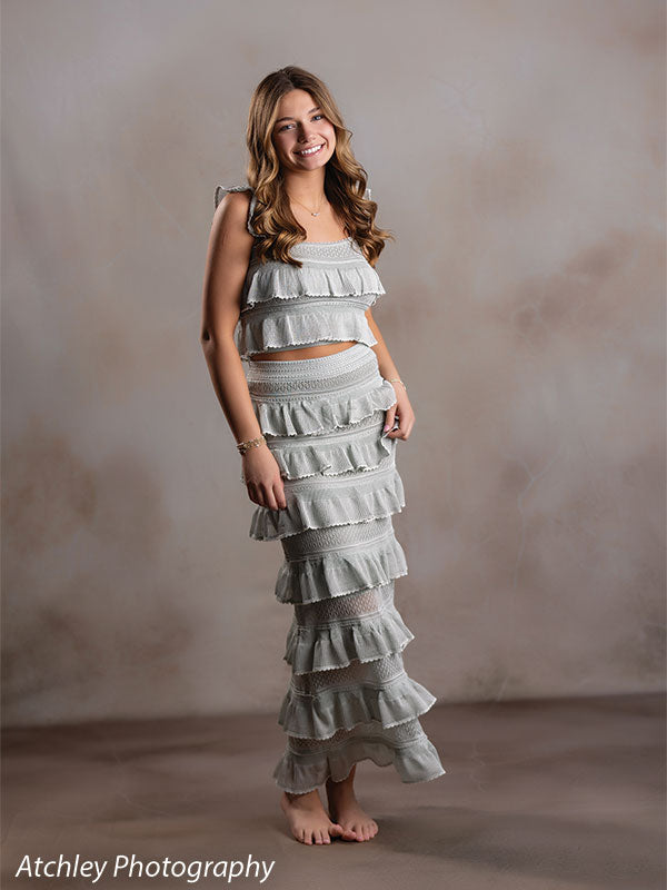 Sand Plaster warm cream plaster texture photography backdrop shown with a senior girl standing full-length in a sage-green ruffled dress CP-8762