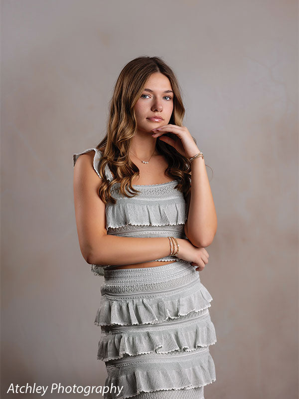 Sand Plaster warm cream plaster texture photography backdrop shown with a senior girl in a sage-green dress seated with hand near her chin CP-8762