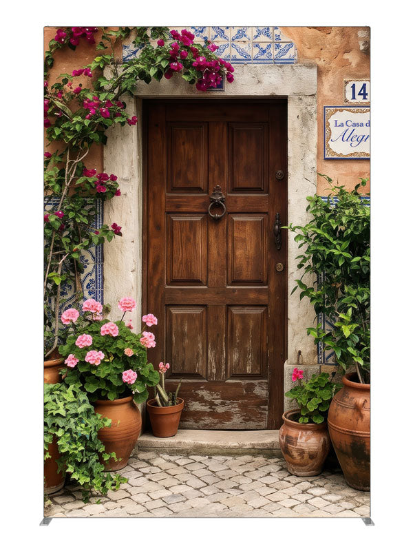 A carved wood door in a peach-terracotta Spanish facade with bougainvillea and potted geraniums, 5ft photography backdrop panel for Denny StudioEdge silicone edge frame