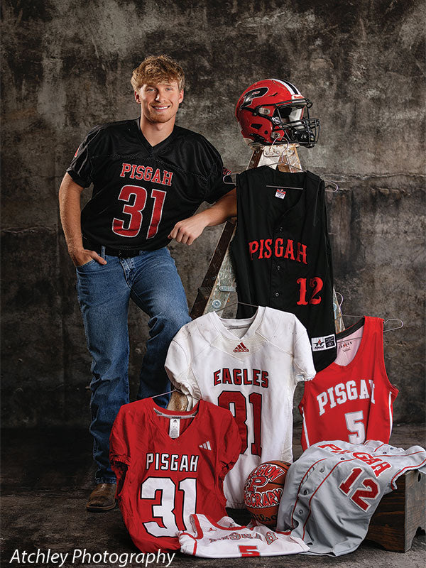 Athletic grunge gray backdrop with high school football, basketball, and baseball jerseys, helmet, and a senior boy, ideal for varsity sports senior portrait sessions.