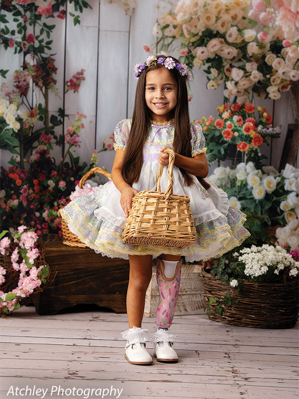 Spring floral backdrop featuring a young girl in a pastel ruffle dress with an Easter basket, ideal for children’s seasonal photography.