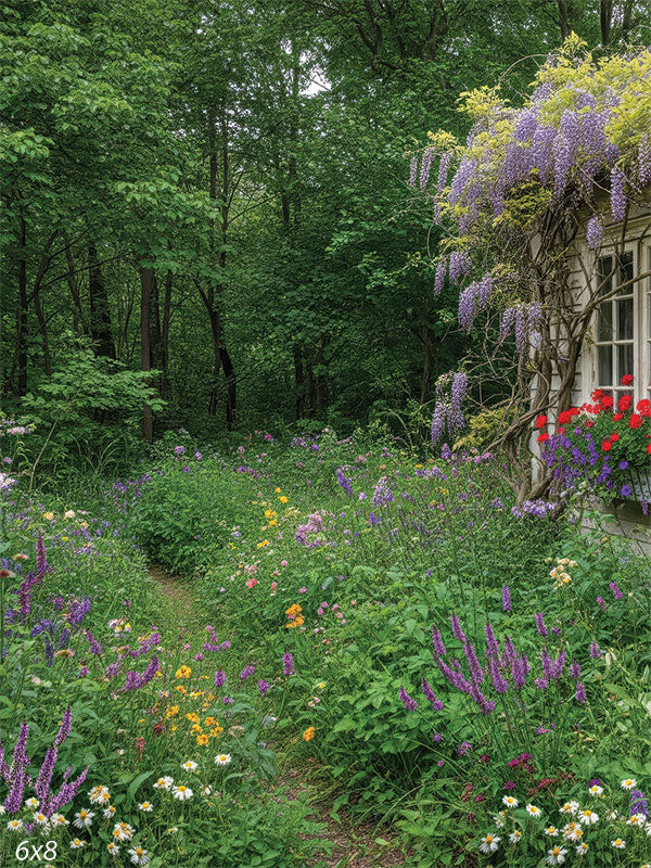 Photography backdrop showing a narrow garden path winding through dense wildflowers toward a shaded forest, with part of a wisteria-covered cottage just visible on the right edge.