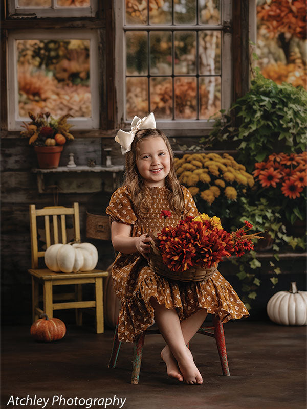 Stained concrete photography floor drop shown with a young girl in a mustard autumn dress seated with a basket of fall flowers on the stained concrete floor in an autumn window scene FD-4148