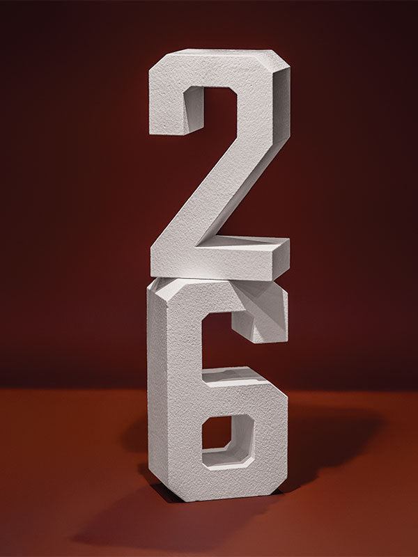 White hard-coated foam stand-alone number props stacked with a 2 balanced on top of a 6 on a red background.