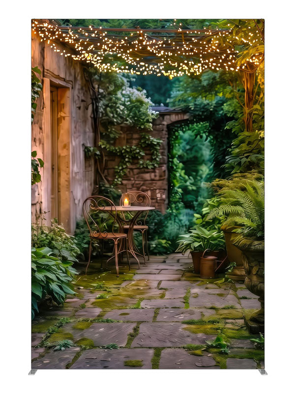 A garden courtyard at dusk under a pergola strung with warm fairy lights, with a bistro table and ferns, 5ft photography backdrop panel for Denny StudioEdge silicone edge frame