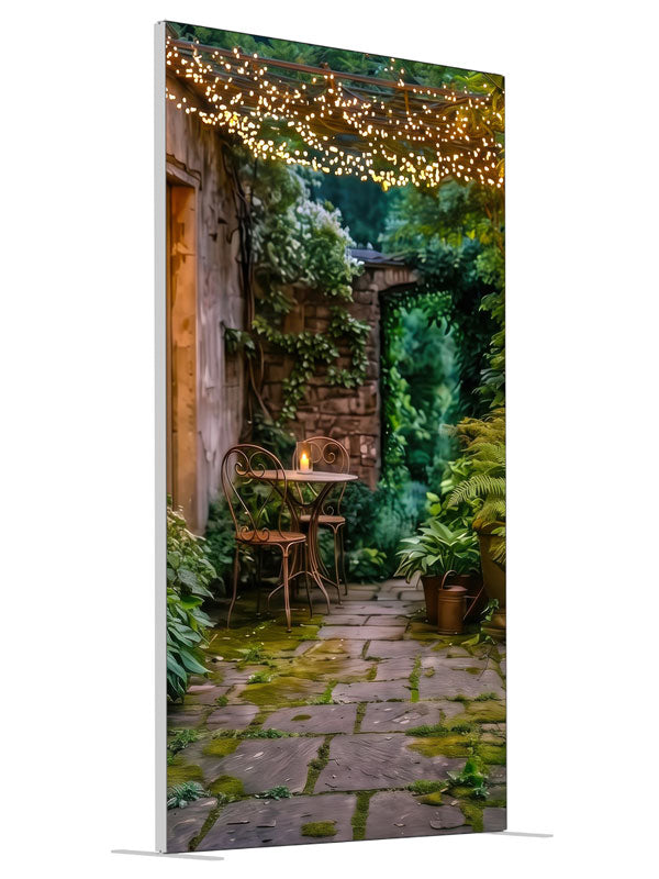 A garden courtyard at dusk under a pergola strung with warm fairy lights, with a bistro table and ferns, 4ft photography backdrop panel for Denny StudioEdge silicone edge frame, angled view