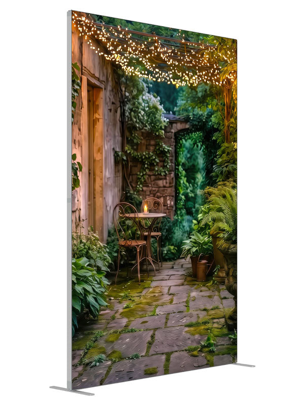 A garden courtyard at dusk under a pergola strung with warm fairy lights, with a bistro table and ferns, 5ft photography backdrop panel for Denny StudioEdge silicone edge frame, angled view