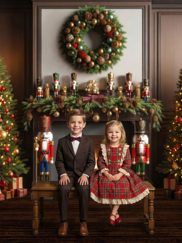 Sugarplum Hearth dark wood mantel fireplace with nutcracker soldiers photography backdrop shown with a young boy and girl seated on a bench in holiday attire CP-8926