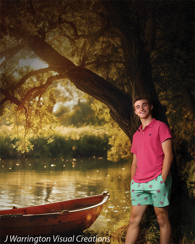 Senior boy standing by a tree in front of a sunlit lake and red rowboat backdrop, perfect for casual summer-inspired portrait sessions.