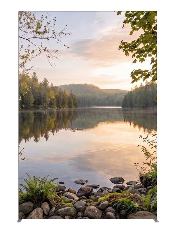 Still forest lake at sunrise with a mirrored peach sky and a mossy stone shoreline, 5ft photography backdrop panel for Denny StudioEdge silicone edge frame