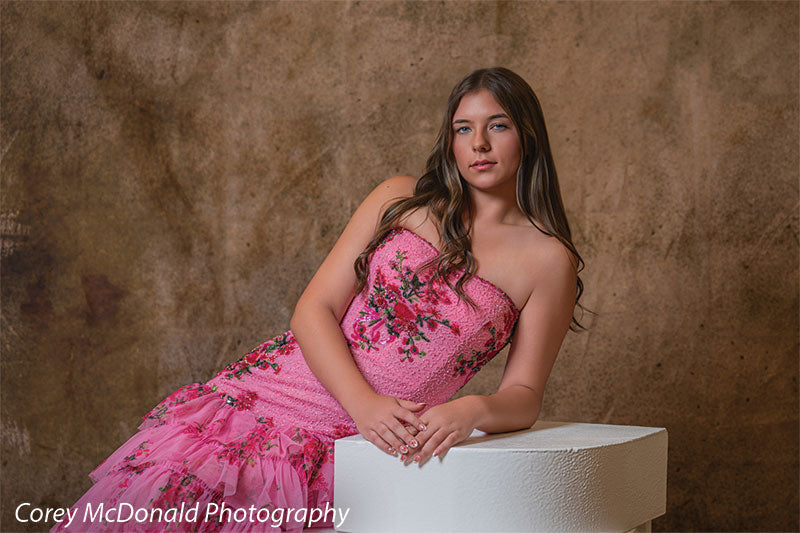 Textured Gold Radiance printed photography backdrop shown in a styled studio session with a senior in a pink floral gown leaning on a white posing step with hands clasped OM-2606