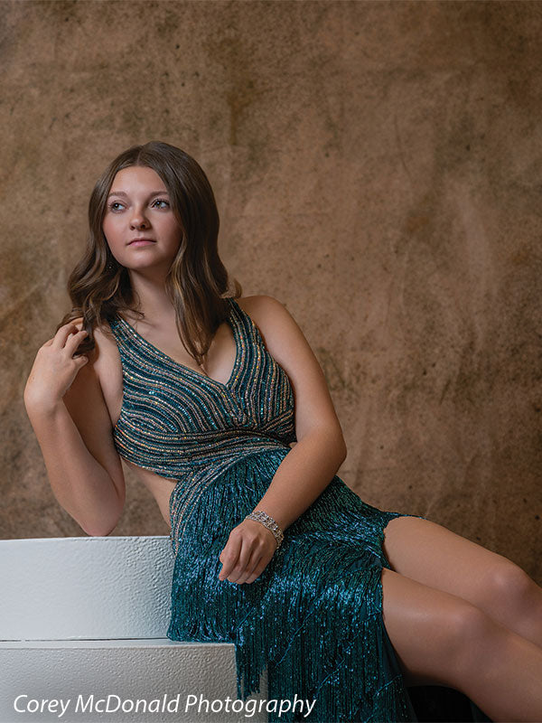 Textured Gold Radiance printed photography backdrop shown in a styled studio session with a senior in a teal fringed gown seated on a white posing step glancing upward OM-2606