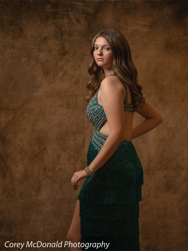 Textured Gold Radiance printed photography backdrop shown in a styled studio session with a senior in a teal fringed gown standing in side profile, looking toward the camera OM-2606
