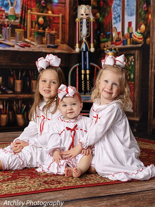Tinker's Bench Santa's workshop toy-room photography backdrop shown as part of a Santa's workshop Christmas corner set with three young girls in white Christmas nightgowns seated by a nutcracker CP-8944