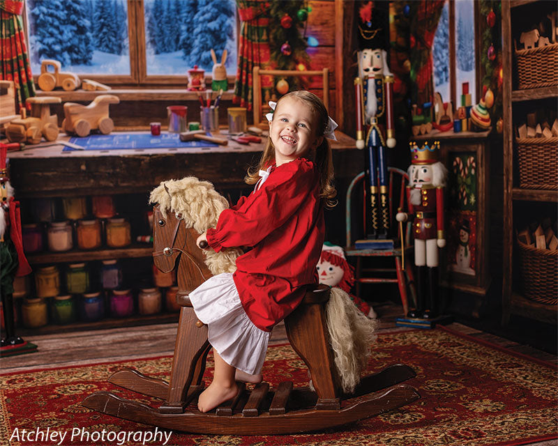 Tinker's Bench Santa's workshop toy-room photography backdrop shown as part of a Santa's workshop Christmas corner set with a young girl in a red dress on a wooden rocking horse, wide view CP-8944