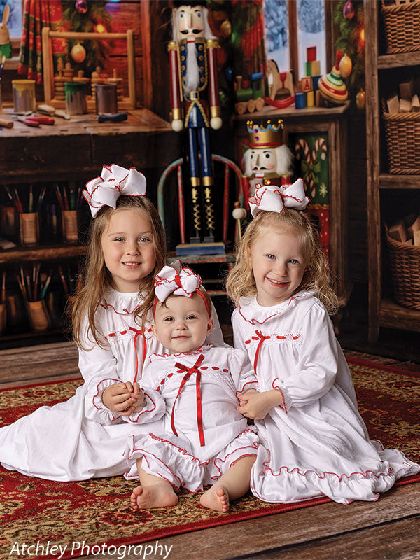 Toy Maker Santa's workshop craft-table photography backdrop shown as part of a Santa's workshop Christmas corner set with three young girls in white Christmas nightgowns seated together CP-8943