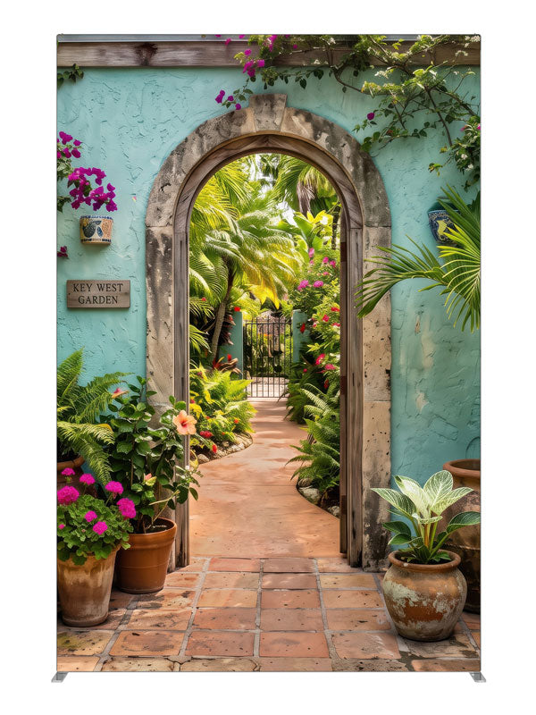 A turquoise stucco courtyard wall with a stone archway opening onto a lush tropical garden, 5ft photography backdrop panel for Denny StudioEdge silicone edge frame