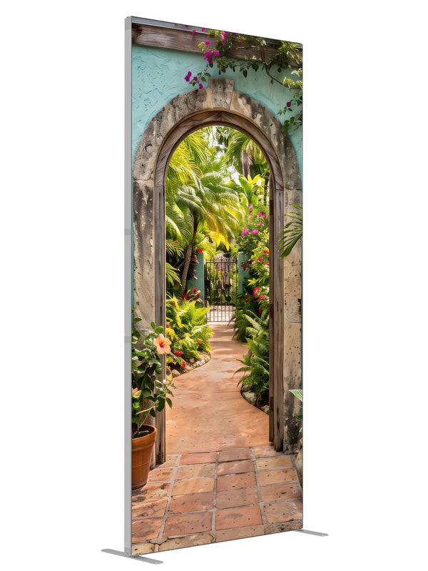 A turquoise stucco courtyard wall with a stone archway opening onto a lush tropical garden, 3ft photography backdrop panel for Denny StudioEdge silicone edge frame, angled view