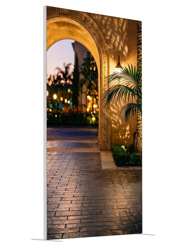 Warm stucco archway opening onto a twilight garden courtyard with a glazed urn and bokeh lights, 4ft photography backdrop panel for Denny StudioEdge silicone edge frame, angled view