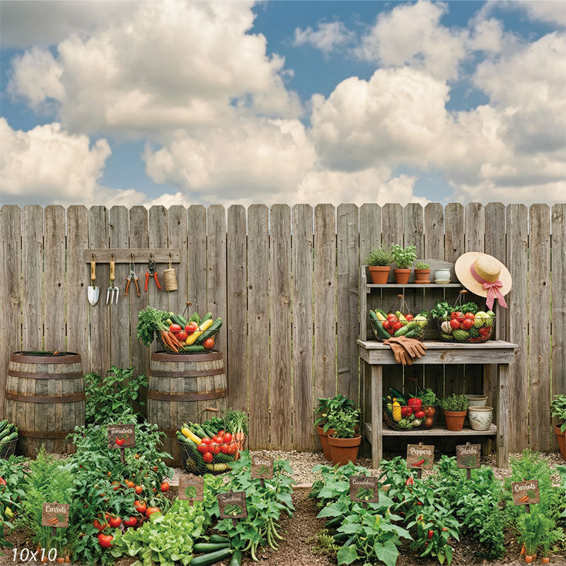 Printed photography backdrop featuring a rustic vegetable garden with a wooden fence, barrel, and garden tools for summer and fall portrait sessions.