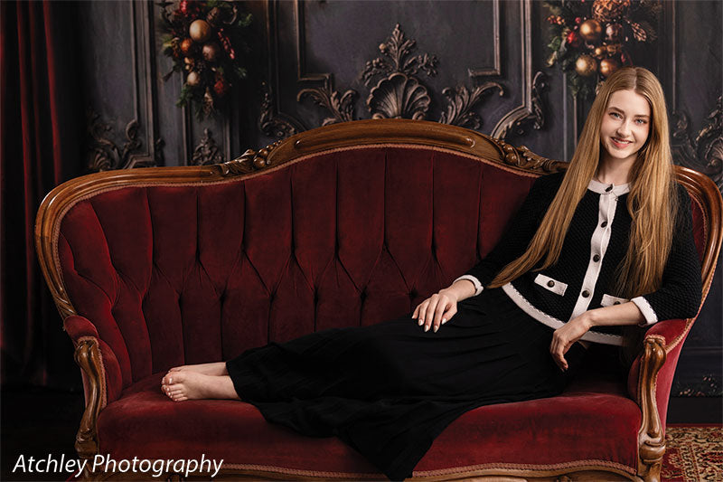 Velvet Swag ornate gray paneled wall with red velvet draping photography backdrop shown with a senior girl reclining on the red velvet sofa, wide view CP-8899