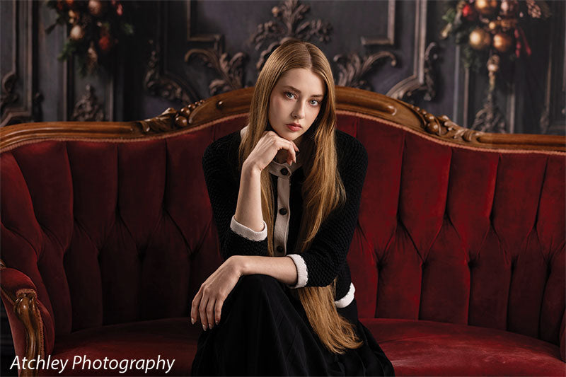 Velvet Swag ornate gray paneled wall with red velvet draping photography backdrop shown with a senior girl seated at the center of the red velvet sofa, wide view CP-8899