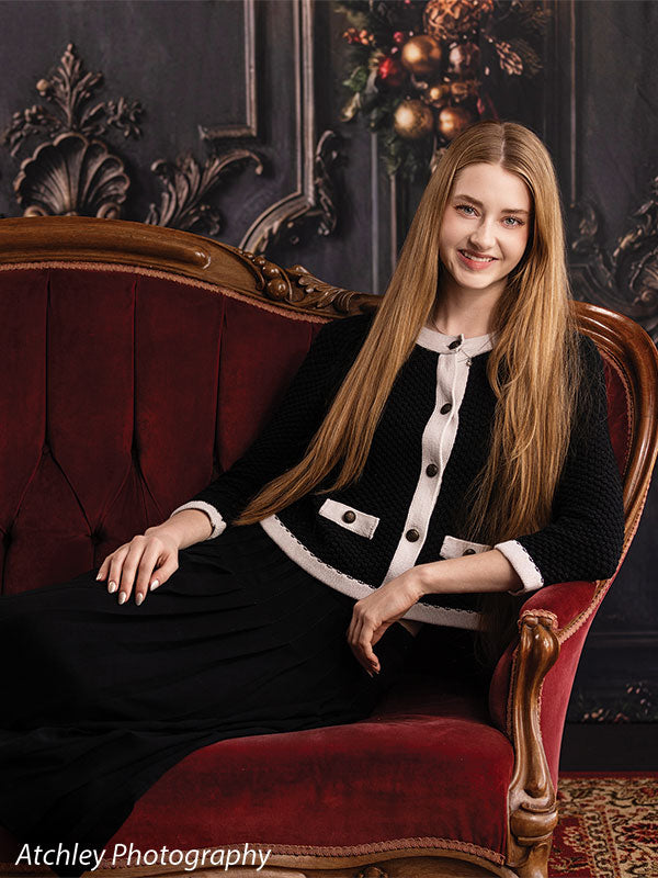 Velvet Swag ornate gray paneled wall with red velvet draping photography backdrop shown with a senior girl seated on the red velvet sofa and smiling CP-8899