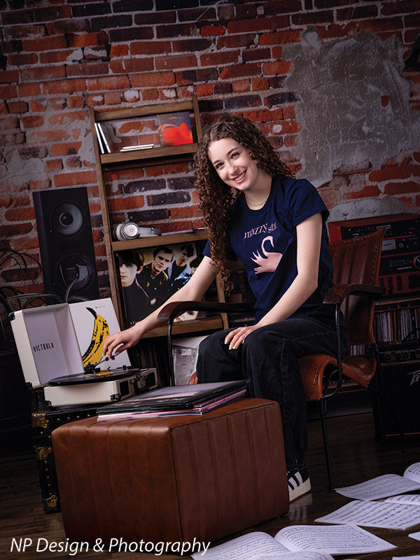 Vintage exposed brick music studio photography backdrop shown with a senior girl seated reaching toward a record turntable, smiling CP-8630