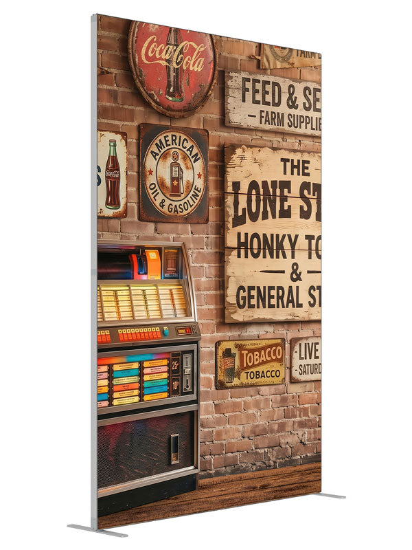 A lit retro jukebox against a red-brick wall of vintage-style roadhouse signage over a plank floor, 5ft photography backdrop panel for Denny StudioEdge silicone edge frame, angled view