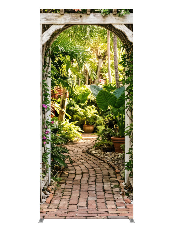 A whitewashed wood arbor in a cream wall opening onto a lush tropical garden with a brick path, 3ft photography backdrop panel for Denny StudioEdge silicone edge frame
