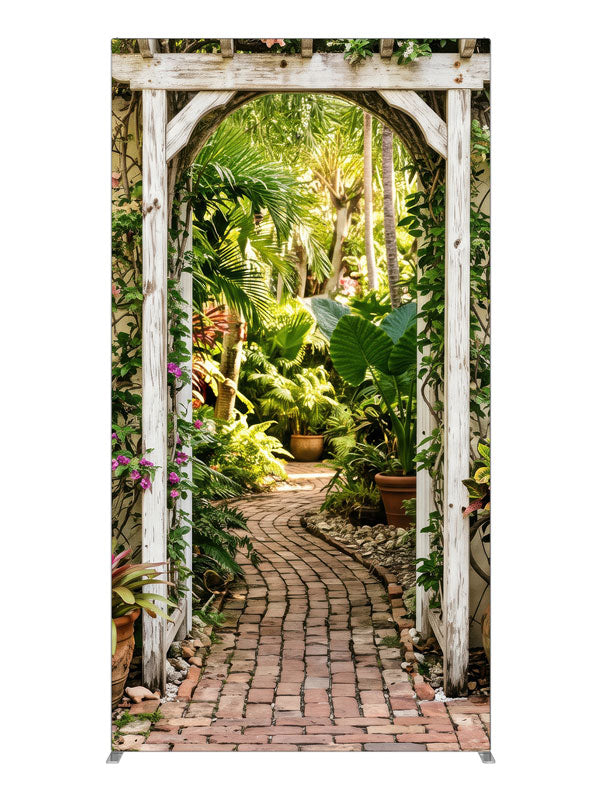 A whitewashed wood arbor in a cream wall opening onto a lush tropical garden with a brick path, 4ft photography backdrop panel for Denny StudioEdge silicone edge frame