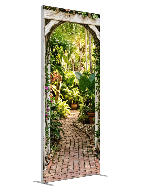 A whitewashed wood arbor in a cream wall opening onto a lush tropical garden with a brick path, 3ft photography backdrop panel for Denny StudioEdge silicone edge frame, angled view
