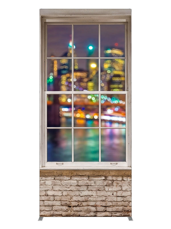 A whitewashed-brick loft with white-framed windows over a colorful bokeh city skyline at night, 3ft photography backdrop panel for Denny StudioEdge silicone edge frame