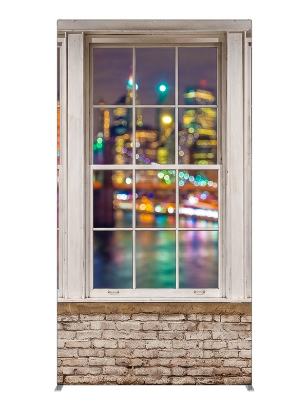 A whitewashed-brick loft with white-framed windows over a colorful bokeh city skyline at night, 4ft photography backdrop panel for Denny StudioEdge silicone edge frame
