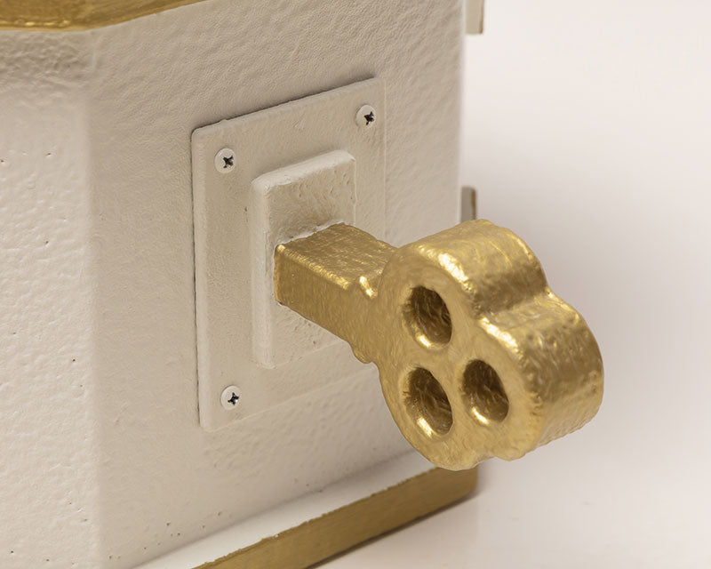 Detailed close-up of gold wind-up key on the white and gold music box prop, adding a luxurious touch to music-inspired photography scenes.