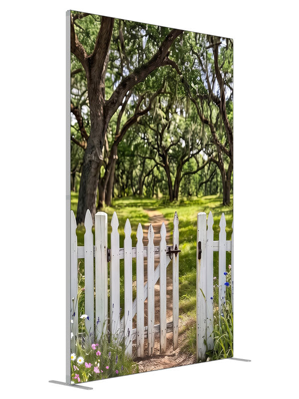 Open white picket gate in a low fence with a dirt path leading into a moss-draped live oak grove, 5ft photography backdrop panel for Denny StudioEdge silicone edge frame, angled view
