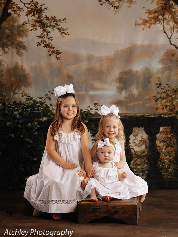 Wood Stack Stool prop set shown with three young girls in white dresses seated together on the wood stack stool bench against a painted ivy terrace backdrop SS-1