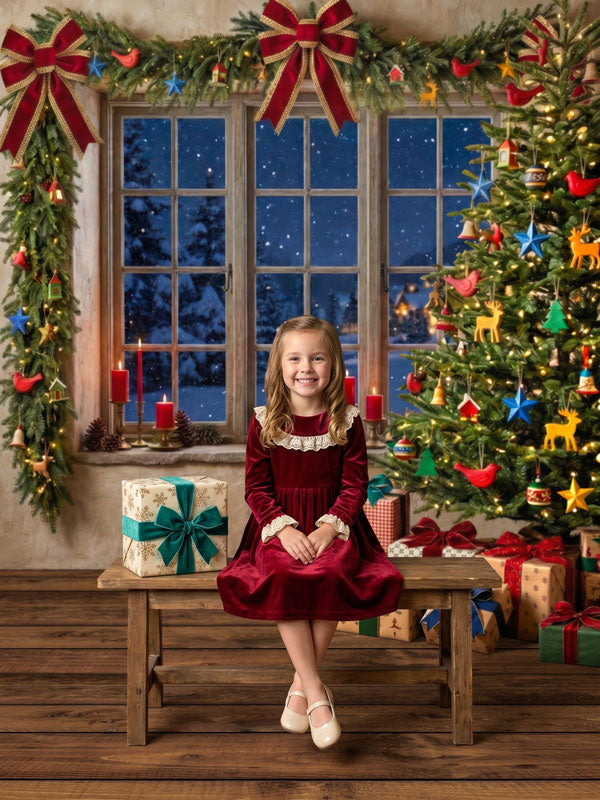 Yule Nook garland window and Christmas tree photography backdrop shown with a young girl in a red velvet dress seated on a wooden bench CP-8895