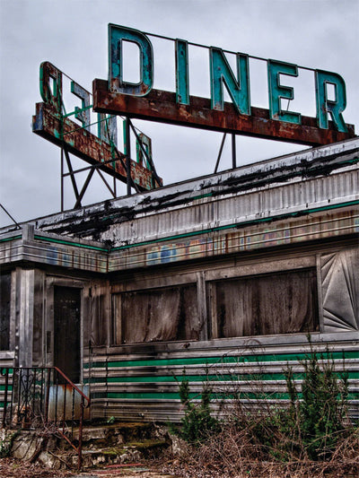 Abandoned Retro Diner Photography Backdrop - Abandoned diner with rusted metal panels, chipping turquoise "DINER" sign, grimy windows, and overgrown plants, evoking nostalgia and decay.