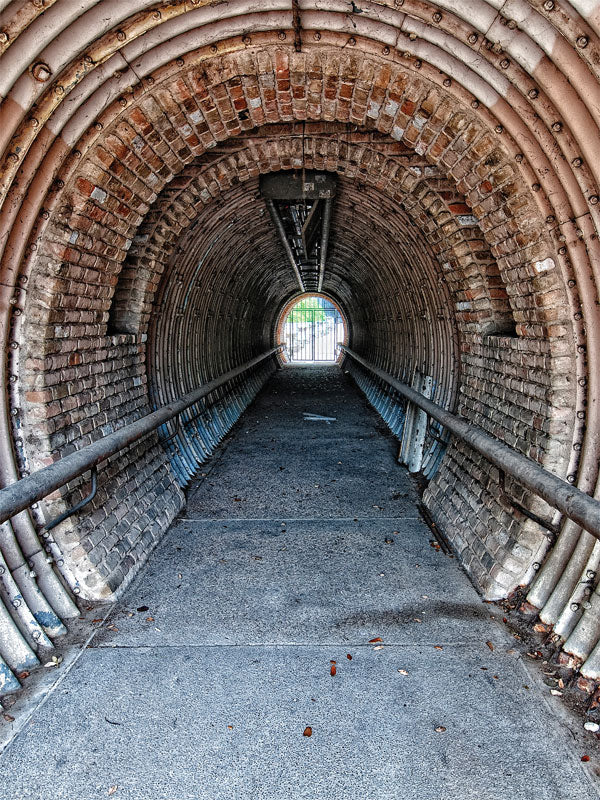 Austin Rustic Urban Tunnel Photo Backdrop - Rustic tunnel with brick and metal arched structure, leading to a bright exit framed by a metal gate.