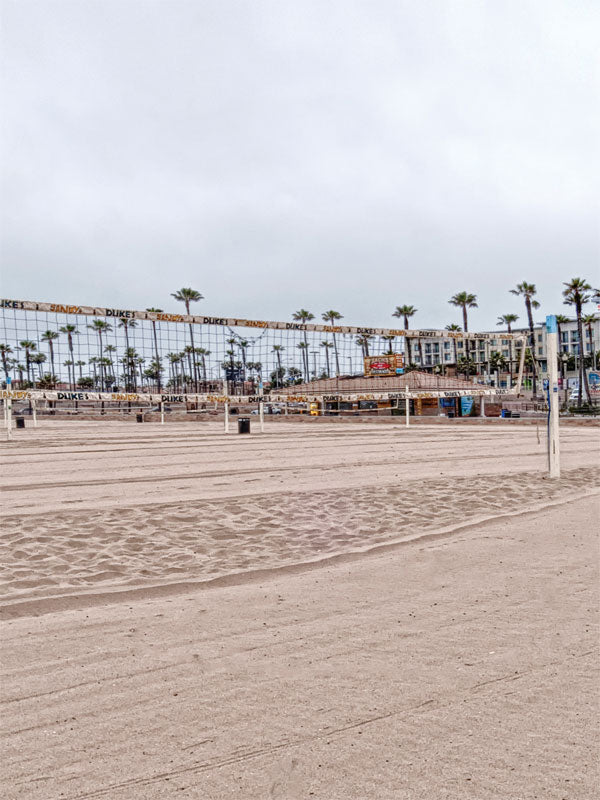 Beach Volleyball Court Photography Backdrop - Beach volleyball court with palm trees and sand, ideal for sports or outdoor-themed photoshoots.