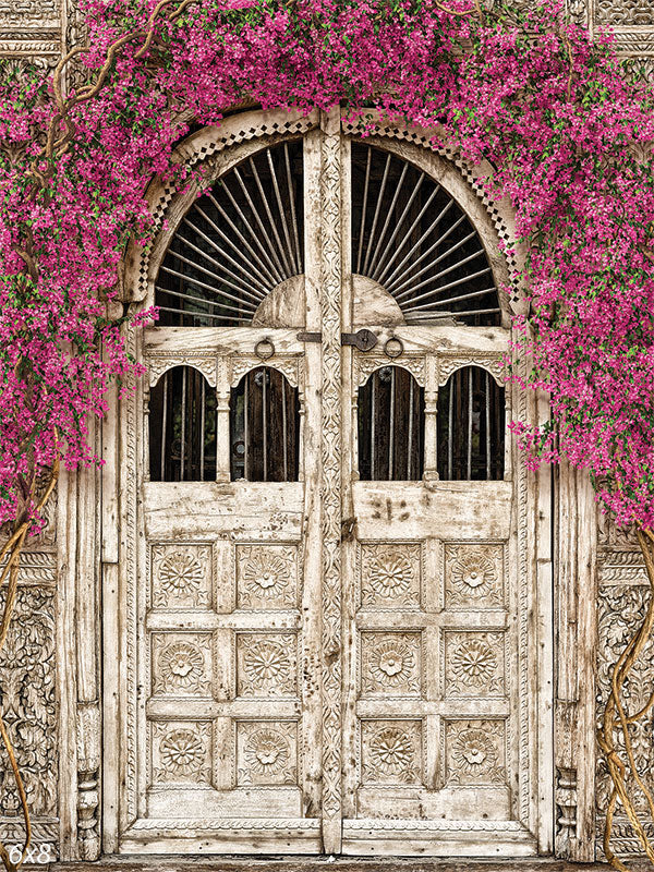 Blooming Antique Doorway Photography Backdrop - An antique carved wooden door adorned with cascading pink flowers, perfect as a photography backdrop.