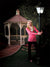 Brick-paved path leading to gazebo with trimmed hedges and soft greenery.