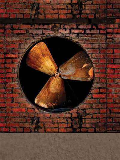 Centered industrial fan set into distressed red brick wall with moody lighting.