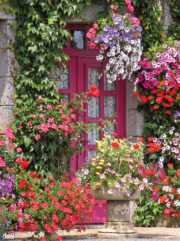 Charming Floral Doorway Photography Backdrop - Photography backdrop featuring a bright pink door framed by ivy-covered stone walls, surrounded by colorful flowers in full bloom, with hanging flower baskets and an ornate stone planter filled with vivid blossoms.