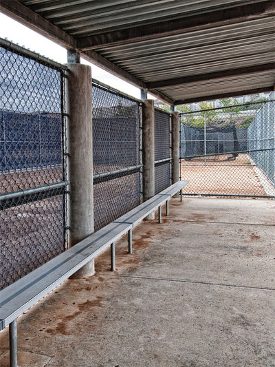 Classic Baseball Dugout Backdrop - Baseball dugout with grey metal bench, chain-link fencing, and corrugated metal roof, capturing an authentic sports setting.