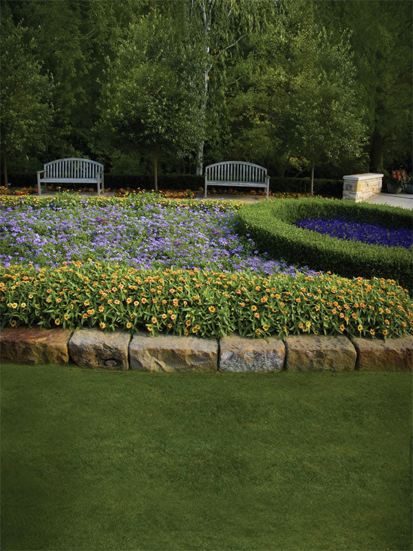Symmetrical garden with stone benches, flower beds, and trimmed hedges.