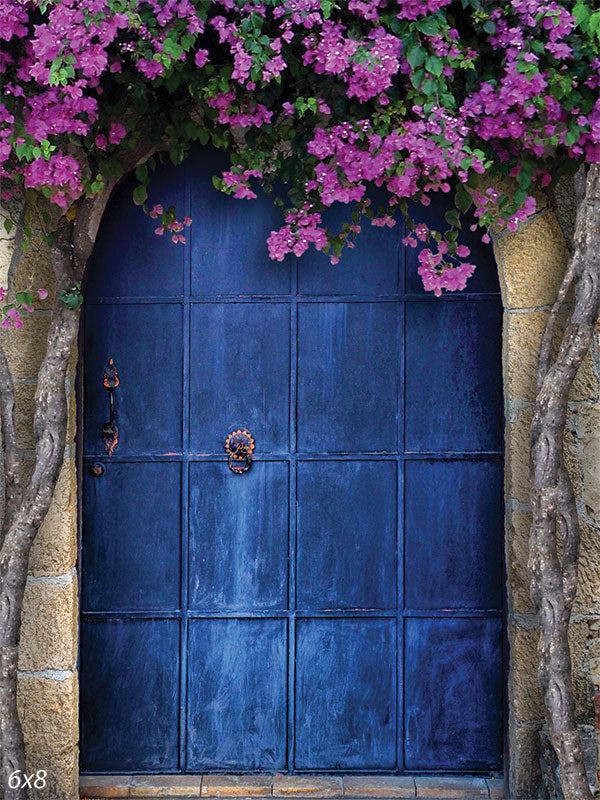 Floral Blue Door Photography Backdrop - Photography backdrop featuring a deep blue door framed by a stone arch and adorned with cascading purple flowers.