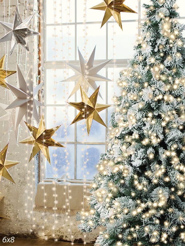 Golden Star Christmas Tree Photography Backdrop - A Christmas tree adorned with lights, snow, and golden stars hanging near a large window, perfect for holiday-themed photoshoots.