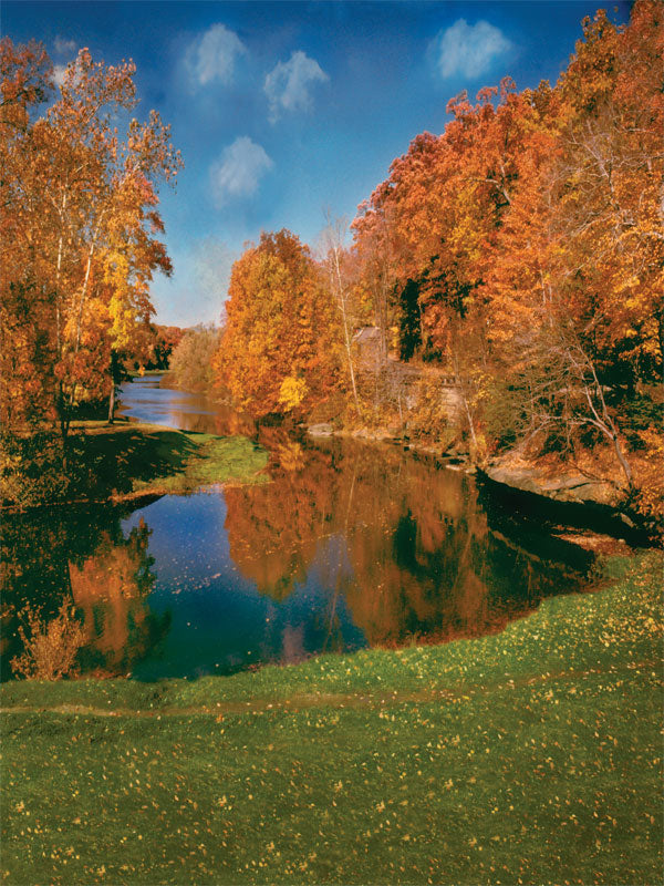 Vivid autumn landscape with trees reflected in a still lake under a clear blue sky.